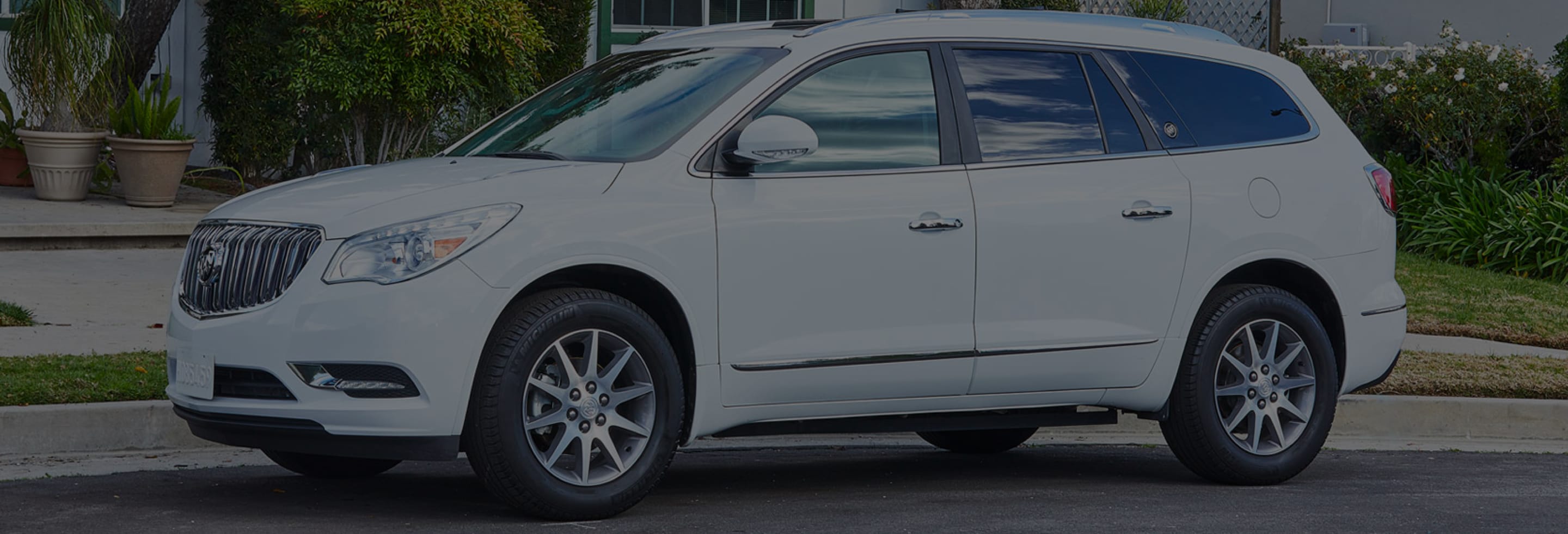 A white Buick car parked outside a house.
