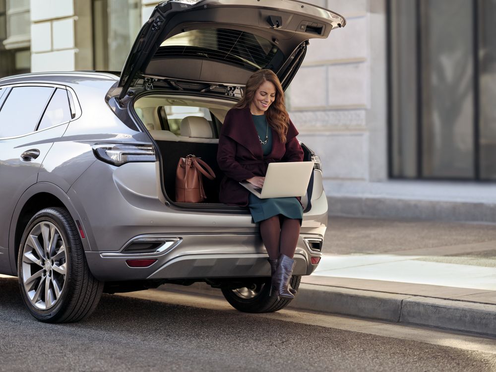 woman sitting in car looking at laptop