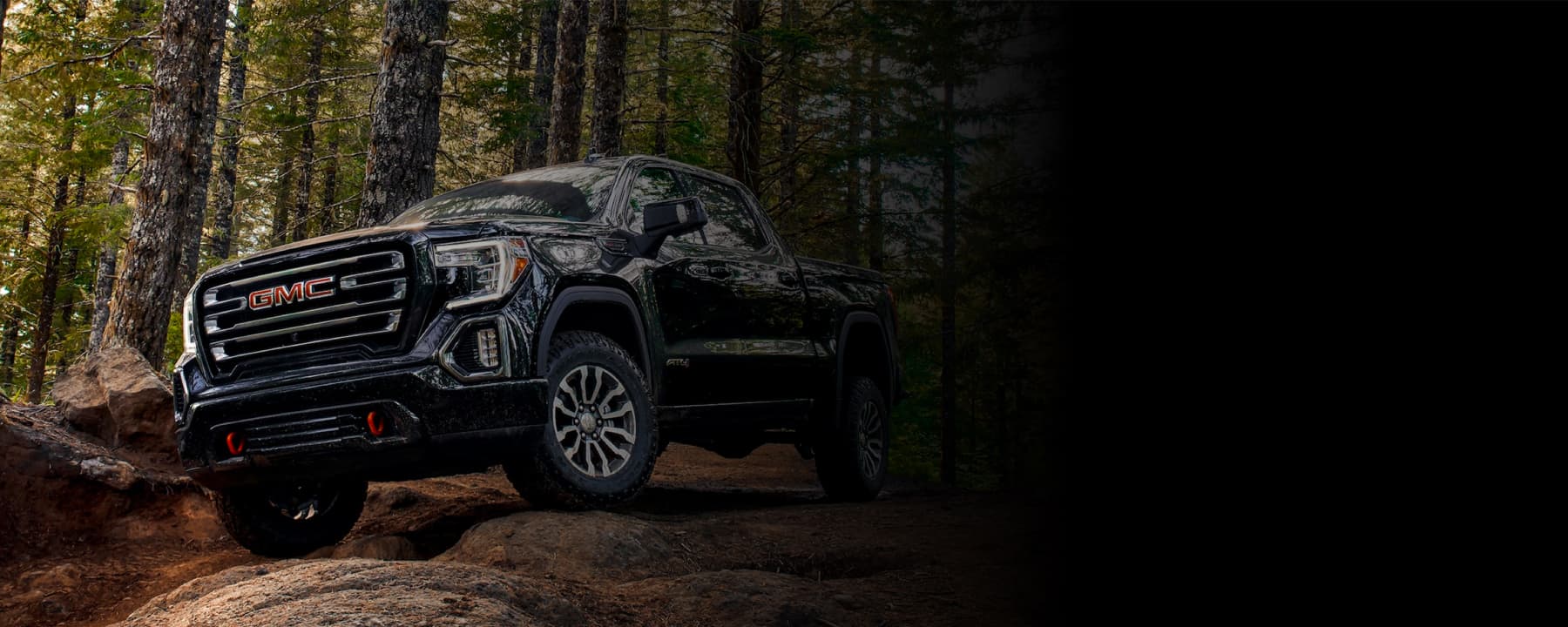 A GMC truck parked on top of a hill in a forest.
